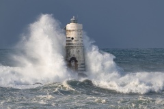 Powerful waves crashing against a Mangiabarche lighthouse during a hurricane, symbolizing resilience and the forces of nature