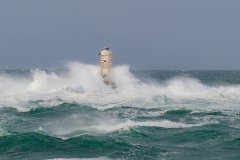 Powerful waves crashing against a Mangiabarche lighthouse during a hurricane, symbolizing resilience and the forces of nature