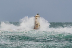 Powerful waves crashing against a Mangiabarche lighthouse during a hurricane, symbolizing resilience and the forces of nature