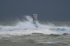 Powerful waves crashing against a Mangiabarche lighthouse during a hurricane, symbolizing resilience and the forces of nature